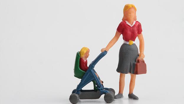 Eine Mutter mit Aktentasche und Kinderwagen