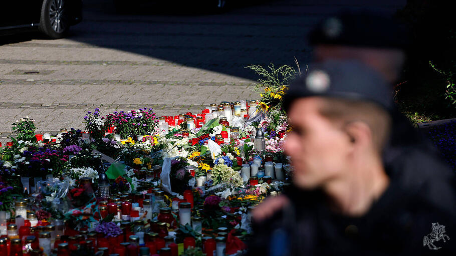 Ein Polizist steht vor einem Blumenmeer.