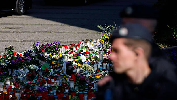 Ein Polizist steht vor einem Blumenmeer.