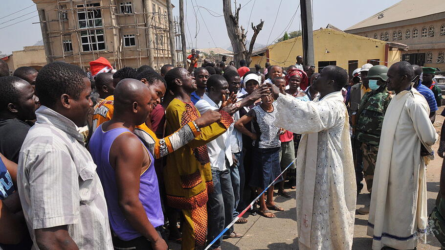Priester versuchen eine Menschenmenge nach einem Terrorangriff auf Gottesdienst-Besucher zu beruhigen.
