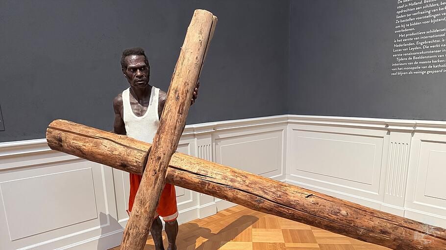 Dieser barf&uuml;&szlig;ige Asmat-Mann befindet sich in einem Raum voller religi&ouml;ser Gem&auml;lde aus dem 15. und 16. Jahrhundert im Lakenhal Museum Leiden: Dort wirkt die lebensechte Skulptur wie ein Aufeinandertreffen zweier sakraler Kulturen. Das lebensgro&szlig;e Kreuz ist Verweis auf die Kreuzigung Jesu &ndash; als Opfer f&uuml;r die Ewigkeit. Auch die Asmat glauben, dass Leben nur durch die Toten m&ouml;glich ist.