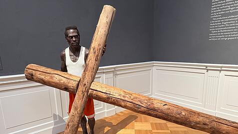 Dieser barf&uuml;&szlig;ige Asmat-Mann befindet sich in einem Raum voller religi&ouml;ser Gem&auml;lde aus dem 15. und 16. Jahrhundert im Lakenhal Museum Leiden: Dort wirkt die lebensechte Skulptur wie ein Aufeinandertreffen zweier sakraler Kulturen. Das lebensgro&szlig;e Kreuz ist Verweis auf die Kreuzigung Jesu &ndash; als Opfer f&uuml;r die Ewigkeit. Auch die Asmat glauben, dass Leben nur durch die Toten m&ouml;glich ist.