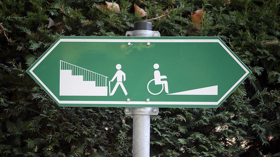 Ein Schild weist den Weg zu einer Rollstuhlrampe.