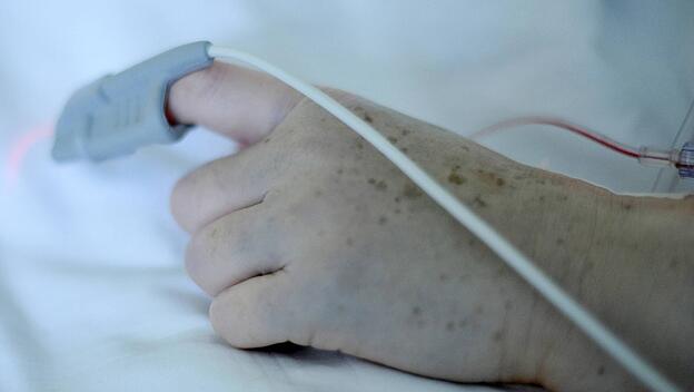 Hand einer Patientin mit Sensor zur kardiologischen Überwachung auf der Intensivstation