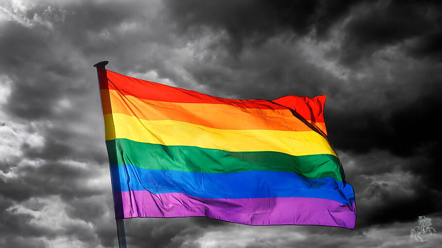 Wehende Regenbogenflagge vor dunklem Himmel