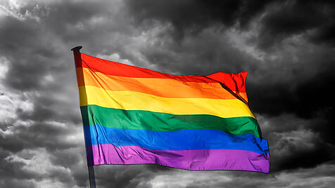 Wehende Regenbogenflagge vor dunklem Himmel
