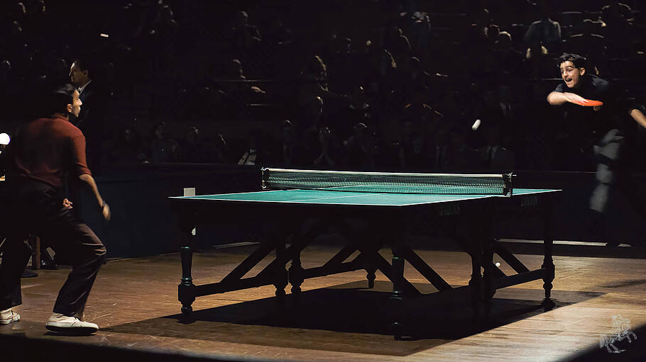 Timoth&eacute;e Chalamet (frontal) schmettert am gr&uuml;nen Tisch: eine Szene aus dem Film &bdquo;Marty Supreme&ldquo;.