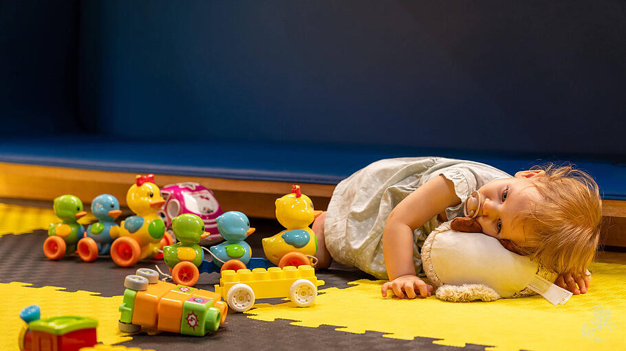 Müdes Kind umgeben von Spielzeug