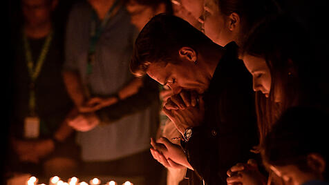 Jugendliche entzünden Kerzen und beten